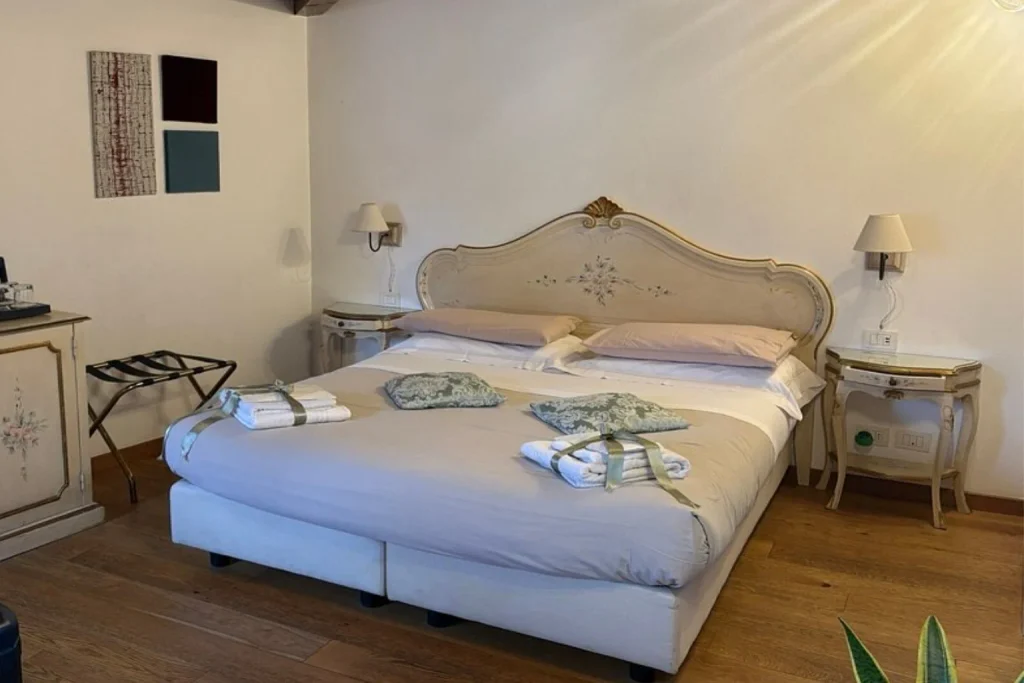 Charming bedroom featuring exposed wooden ceiling beams, a decorative bed, traditional painted furniture and warm wood flooring – Alloggi Ai Tessitori, Venice.