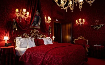 Romantic luxury room with rich red velvet décor, ornate gold furnishings and chandelier, Ca’ Maria Adele, Venice
