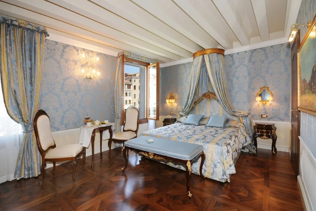 Elegant guest room with blue Venetian décor, a romantic canopy bed and traditional period furnishings, Hotel Canal Grande, Venice.