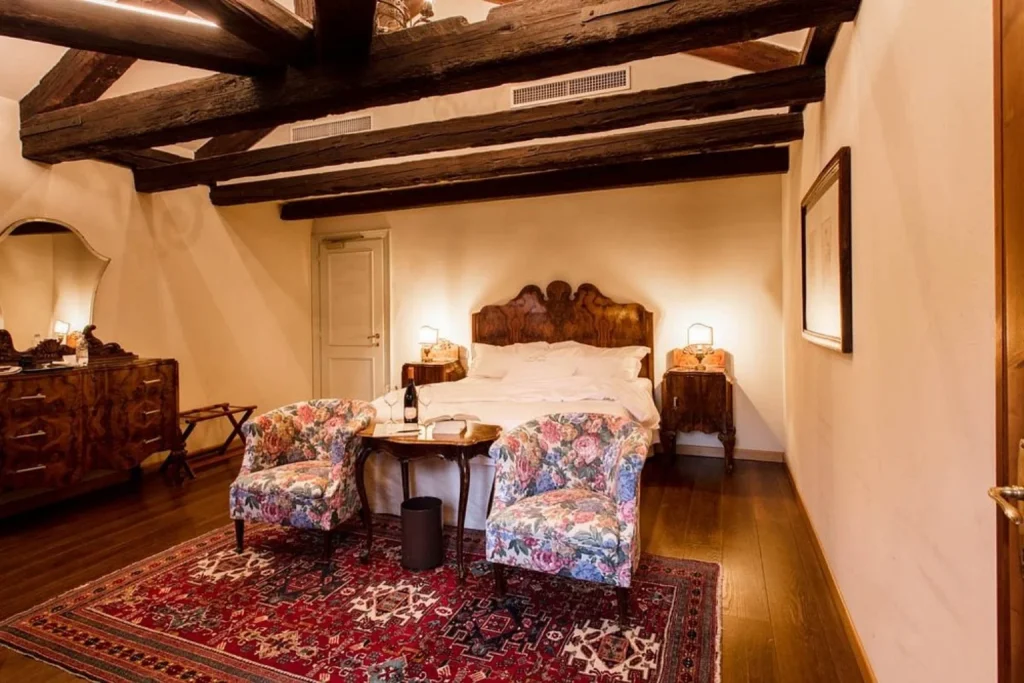 Traditional bedroom with exposed wooden beams at Hotel Flora in San Marco, Venice