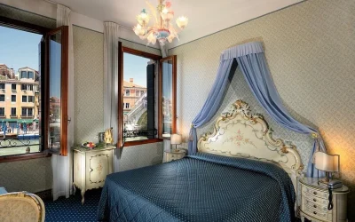 Classic canal view room with Venetian décor, an ornate canopy bed, and views of the Grand Canal at Hotel Rialto in Venice, Italy.