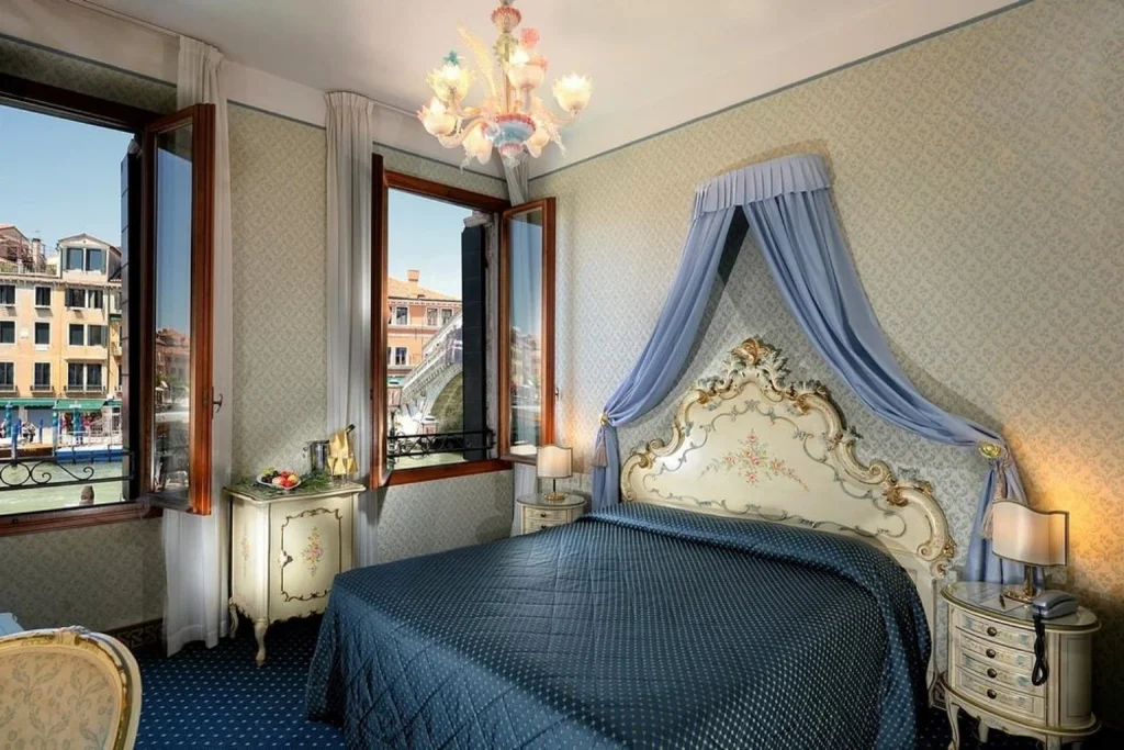 Traditional Venetian-style room with ornate furnishings and direct views of the Rialto Bridge and Grand Canal, Hotel Rialto, Venice.