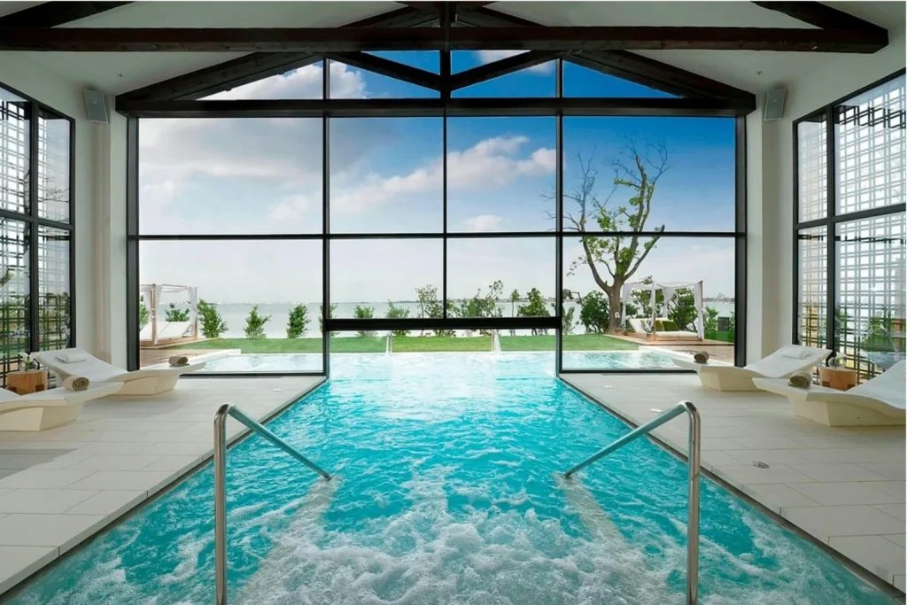 Indoor spa pool at JW Marriott Venice Resort & Spa with floor-to-ceiling windows overlooking the lagoon and gardens.