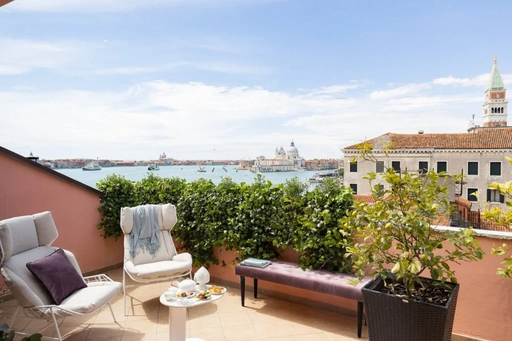 Private rooftop terrace with comfortable seating and sweeping views across the Venetian Lagoon and historic skyline, Londra Palace Venezia, Venice.