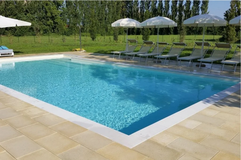 Spacious outdoor swimming pool surrounded by greenery, sun loungers and white umbrellas at Hotel Venice Resort in Venice.