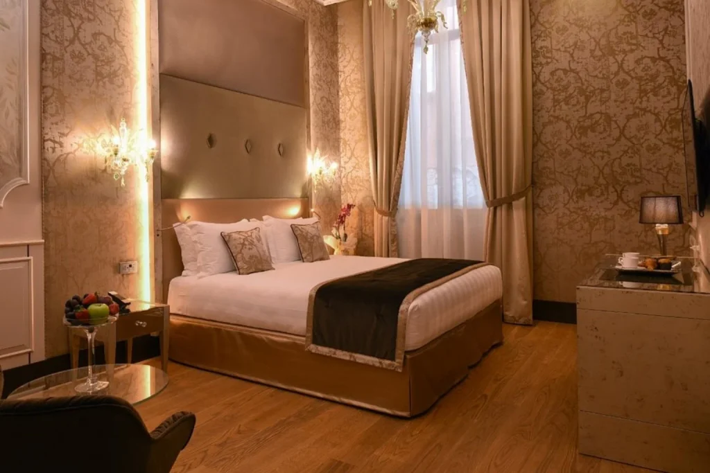 Elegant guest room with a decorative chandelier, warm lighting and sophisticated Venetian-inspired interiors at Santa Croce Boutique Hotel in Venice.
