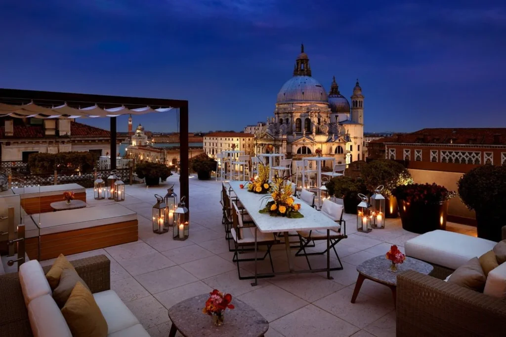 Elegant rooftop terrace with lounge seating and spectacular views of Santa Maria della Salute at dusk, The Gritti Palace, Venice.