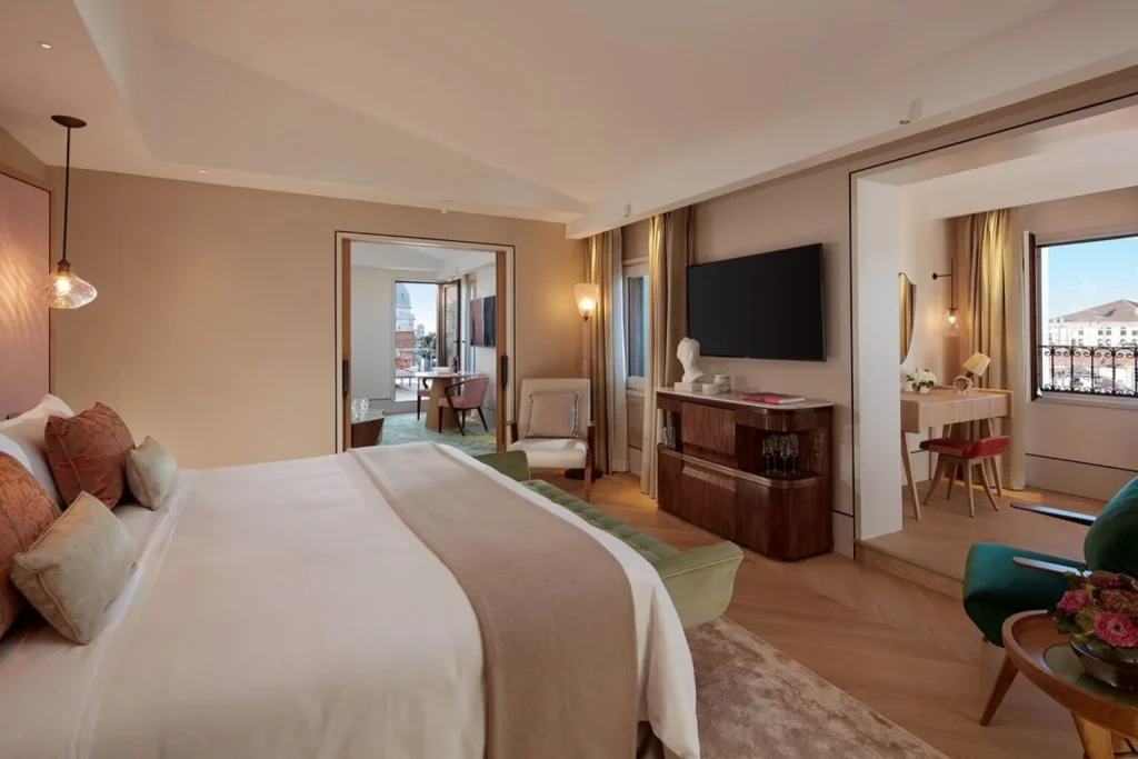 Contemporary luxury bedroom at The St. Regis Venice featuring elegant furnishings, a spacious sitting area and large windows overlooking the city.